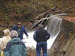 Journalists examine the cement 'floor' built into this man-made Pennsylvania dam.  The dam will be removed in the coming months, to restore the stream to its natural course.